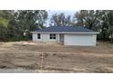 Newly built house with gray siding, two-car garage, and unfinished landscaping at 24268 Sw Tiger Lake W Blvd, Dunnellon, FL 34431