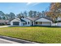 Contemporary single story home with white exterior, gray garage door and landscaping at 4216 Se 7Th Pl, Ocala, FL 34471