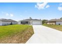 Charming single-story home featuring a gray and white exterior, a spacious driveway, and a well-manicured lawn at 4393 Sw 169 Lane Rd, Ocala, FL 34473