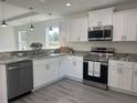 Well-lit kitchen featuring white cabinets, stainless steel appliances, and grey laminate flooring at 4698 Sw Zinnia, Dunnellon, FL 34431