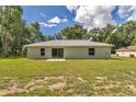 Back exterior view of a home with a light-gray exterior, green lawn, and a sliding glass door at 963 Nw 65Th St, Ocala, FL 34475