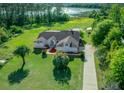 Aerial view of a single-story home with a large yard, long driveway and lake view at 11540 Se Highway 464, Ocklawaha, FL 32179