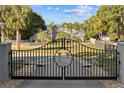 Ornate entry gate with house and lake view at 13041 Se 158Th Ln, Weirsdale, FL 32195