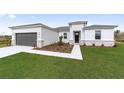 Modern house exterior with gray garage door and stone accents.Landscaped front yard at 3792 Sw 166Th Pl Rd, Ocala, FL 34473