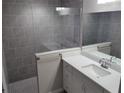 Clean bathroom with gray tile shower, white vanity, and a large mirror at 5 Locust Trak, Ocala, FL 34472