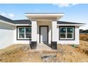 Front view of a new construction home with a white exterior and black accents at 55 Locust Loop Cir, Ocala, FL 34472