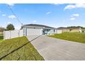 Newly built home with a driveway, white fence, and grassy lawn at 7 Hemlock Radial, Ocala, FL 34472