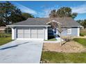 Gray house with a two-car garage and a landscaped yard at 14320 Se 96Th Ct, Summerfield, FL 34491