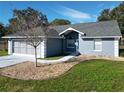 Gray house with a two-car garage and a landscaped yard at 14320 Se 96Th Ct, Summerfield, FL 34491