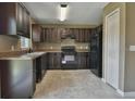 Dark wood cabinets, black appliances, and tile floor at 14448 Sw 75 Cir, Ocala, FL 34473