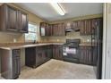 Dark wood cabinets, black appliances, and tile floor at 14448 Sw 75 Cir, Ocala, FL 34473