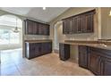 Modern kitchen with dark wood cabinets, granite counters, and tile floors at 6363 Nw 61 Ave, Ocala, FL 34482