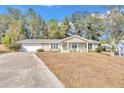 Tan house with white trim, a covered porch, and a spacious yard at 8137 Sw 117Th Loop, Ocala, FL 34481