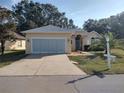 Tan house with attached two-car garage and landscaped yard at 11105 Sw 69Th Cir, Ocala, FL 34476