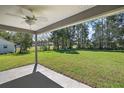 Large backyard with grassy lawn, and a covered patio with ceiling fan at 46 Locust Pass Run, Ocala, FL 34480