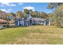 House with a blue exterior, well-manicured lawn, and mature trees at 5579 Se 44Th Cir, Ocala, FL 34480