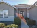 Front entry with a covered porch, dark-colored door, and neatly trimmed landscaping at 8652 Se 133Rd Ln, Summerfield, FL 34491