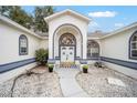 Close up of the double door front entrance with decorative plants, a door mat, and stone landscaping at 7528 Sw 102Nd Loop, Ocala, FL 34476