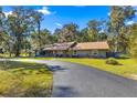 Single story home with a long driveway and lush landscaping at 3650 Se 22Nd Ave, Ocala, FL 34471