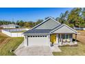 Gray house with yellow door, two-car garage, and landscaped yard at 4709 Se 25Th Loop, Ocala, FL 34480