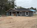 View of a modern, gray home with a new black roof and white trim under a cloudy sky at 5411 Nw 7Th Pl, Ocala, FL 34482