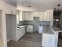 Bright kitchen featuring white cabinets, gray countertops, and wood-style flooring at 5411 Nw 7Th Pl, Ocala, FL 34482