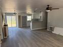Spacious living room with modern grey flooring open to kitchen with white cabinetry and stone countertops at 5411 Nw 7Th Pl, Ocala, FL 34482