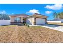 Single-Gathering home featuring a two-car garage, stone accents, manicured lawn, and bright natural light at 7646 Sw 129Th Pl, Ocala, FL 34473