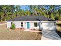 One-story house with gray siding, teal door and attached garage, on a grassy lot at 2295 Sw 142Nd Court Rd, Ocala, FL 34481