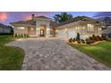 Elegant home at dusk featuring a three-car garage and lush landscaping at 7549 Nw 33Rd Pl, Ocala, FL 34482