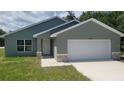 Well-maintained single-story home with a white garage door, stone accents, and green lawn at 24300 Sw Sea Cliff Ave, Dunnellon, FL 34431