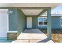 Covered front porch with stone accents and a white door at 53 Guava Pl, Ocklawaha, FL 32179