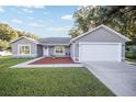 Gray house with white garage door, landscaping, and walkway at 66 Teak Loop, Ocala, FL 34472