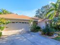 Tan one-story house with a two-car garage and lush landscaping at 8990 Se 178Th Muirfield Pl, The Villages, FL 32162