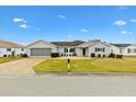 One-story home with light grey siding, a two-car garage, and well-manicured lawn at 9836 Se 175Th Pl, Summerfield, FL 34491