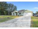 House exterior featuring a green facade, two-car garage, and well-maintained lawn at 13165 Sw 107Th St, Dunnellon, FL 34432