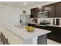 Modern kitchen with dark brown cabinets, stainless steel appliances, and an island at 8511 Las Palmas Way, Wildwood, FL 34785