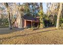 Rustic red house with stone accents nestled amongst large trees with Spanish moss at 876 Ne 71St Ln, Ocala, FL 34479