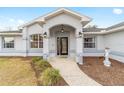 Front entryway with arched entry, gray columns, and landscaping at 10628 Sw 74Th Ave, Ocala, FL 34476