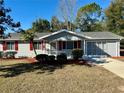 Single story home features a gray exterior, red shutters, and a spacious lawn at 11440 Sw 85Th Ave, Ocala, FL 34481