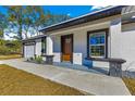 Modern front entrance with gray stone accents and a wood door at 14363 Se 36Th Ct, Summerfield, FL 34491