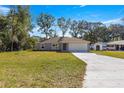 Newly built house showcasing a gray exterior, white garage door, and a spacious front yard at 7084 Se 124 St, Belleview, FL 34420