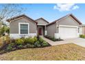 Gray house with a red door, two-car garage, and landscaped yard at 7402 Sw 99Th Ave, Ocala, FL 34481