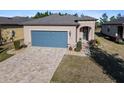 Tan one-story house with gray garage door, landscaped yard, and paver driveway at 7752 Sw 96Th Avenue Rd, Ocala, FL 34481