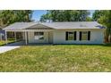 Attractive one-story house featuring a carport and dark shutters, complemented by a lush green lawn at 16434 Se 57 Pl, Ocklawaha, FL 32179