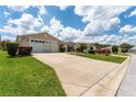 Tan house with a two-car garage, driveway, and landscaped yard at 17606 Se 93Rd Butler Ct, The Villages, FL 32162