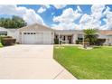 Tan one-story house with a two-car garage and lush green lawn at 17606 Se 93Rd Butler Ct, The Villages, FL 32162