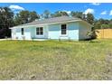 Light blue house with white garage door and a spacious lawn at 4562 Sw Hyacinth Ct, Dunnellon, FL 34431