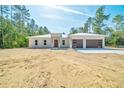 A modern, single-story home boasts a metal roof, wood-accented garage doors, and fresh landscaping at 6877 Sw 131St Cir, Ocala, FL 34481