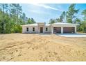 A modern, single-story home boasts a metal roof, wood-accented garage doors, and fresh landscaping at 6877 Sw 131St Cir, Ocala, FL 34481